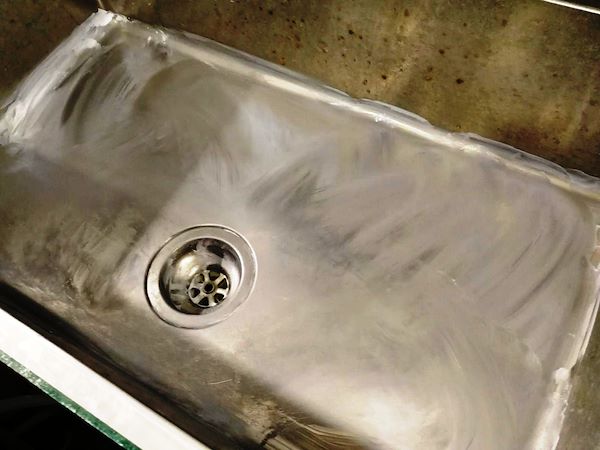 Strofinare energicamente la crema su tutta la superficie dell’acciaio inox. La crema deve essere strofinata tutta fino a diventare un leggero strato di polvere bianca